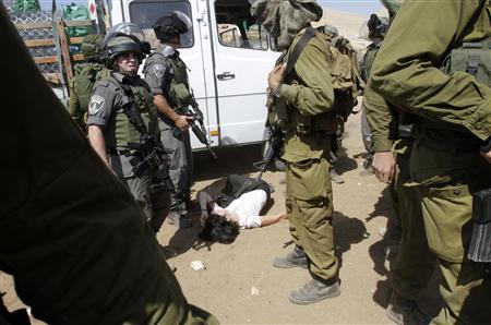 French diplomat Castaing lays on the ground after Israeli soldiers carried her out of her truck containing emergency aid, in the Jordan Valley